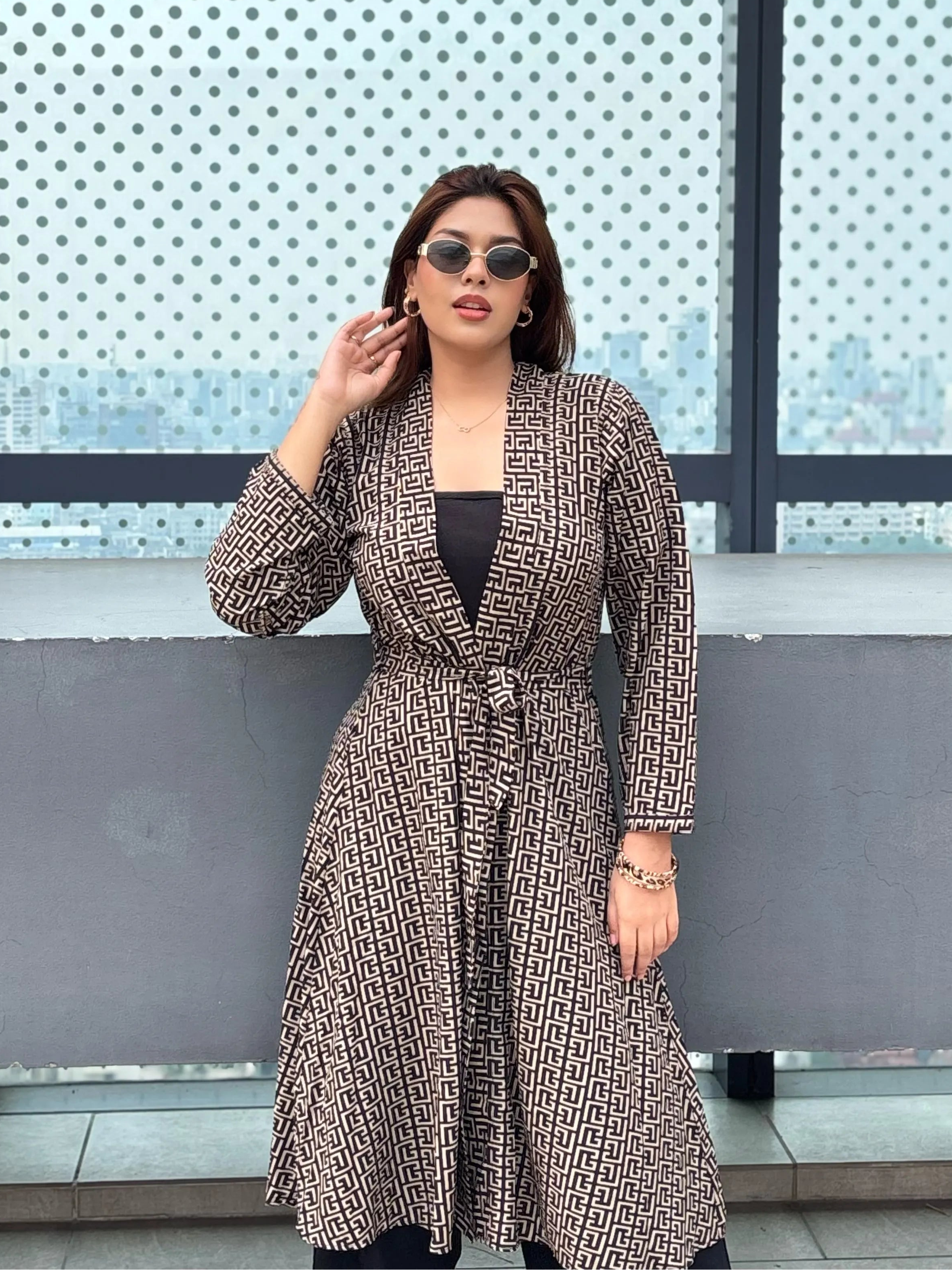 Woman in a patterned Shrug standing in front of a glass wall with a polka dot design.
