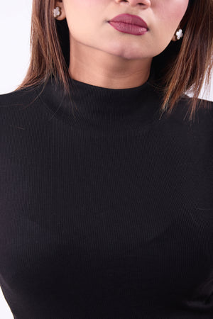 Close-up of a person wearing a black turtleneck sweater with a blurred background