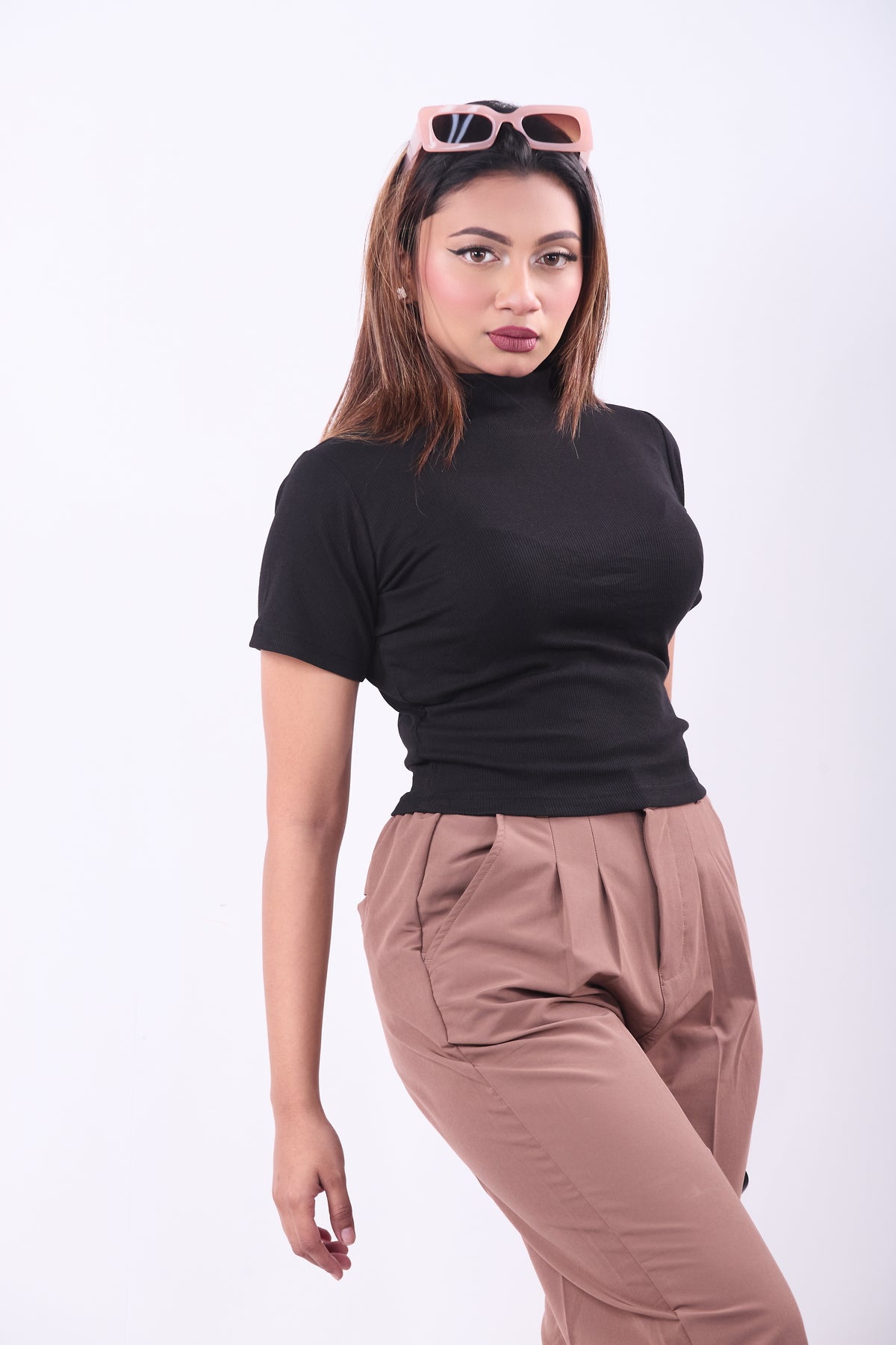 Woman wearing a black turtleneck and brown pants on a white background
