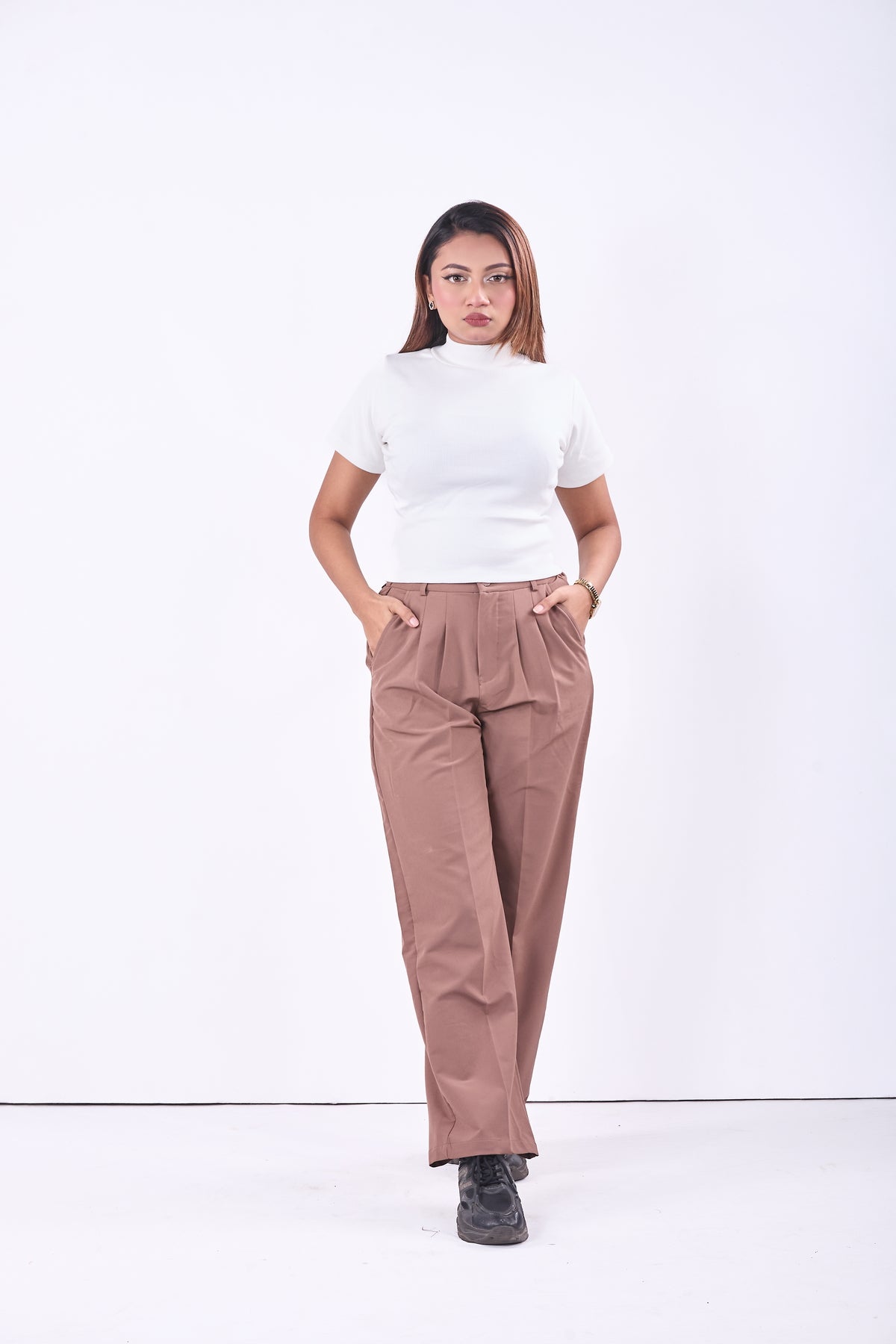 Woman wearing a white top and brown pants on a white background