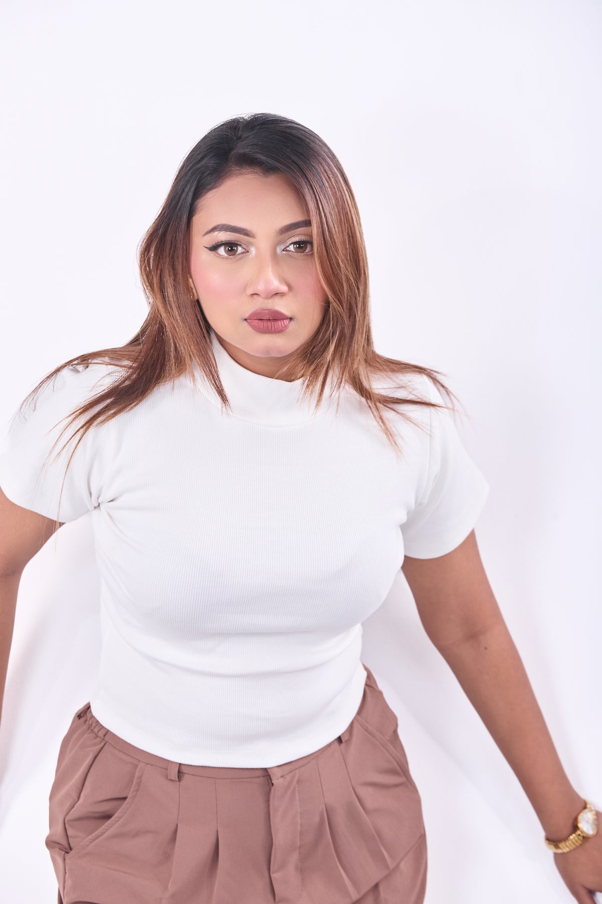 Woman wearing a white top and brown pants on a white background