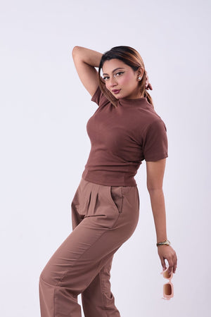 Woman wearing a brown outfit posing against a white background