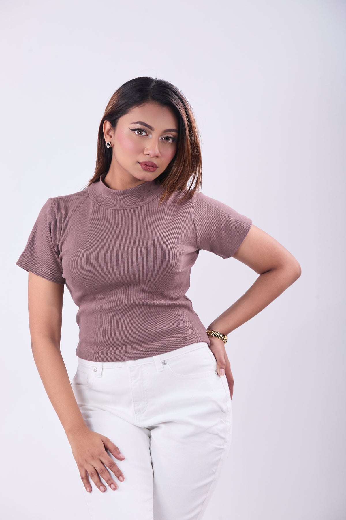 Woman wearing a mauve turtleneck and white pants on a white background