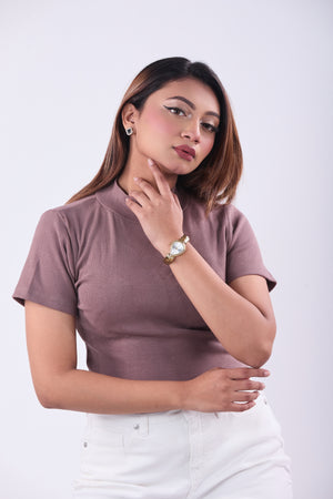 Woman wearing a mauve top and white pants against a plain background