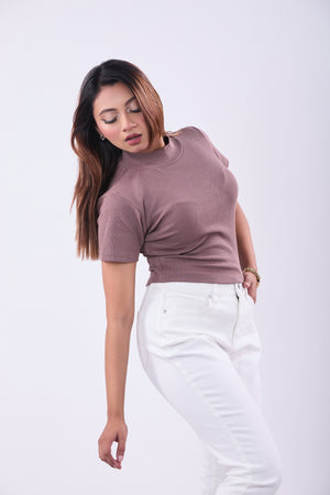 Woman wearing a mauve top and white pants on a white background