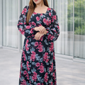 Woman wearing a floral dress standing in front of a glass wall.