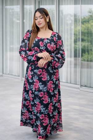 Woman wearing a floral dress standing in front of a glass wall.