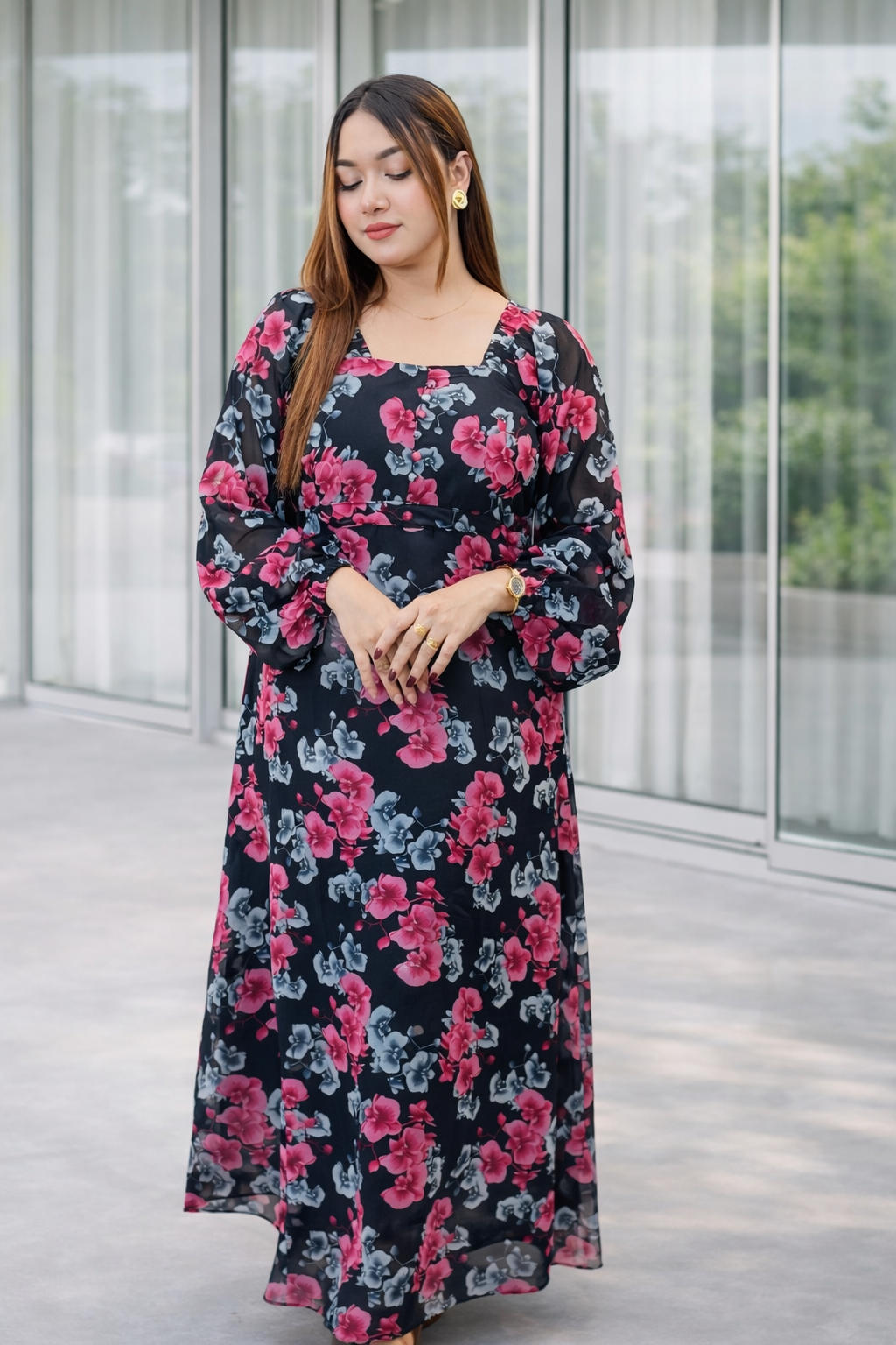 Woman wearing a floral dress standing in front of a glass building.