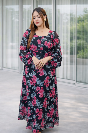 Woman wearing a floral dress standing in front of a glass building.