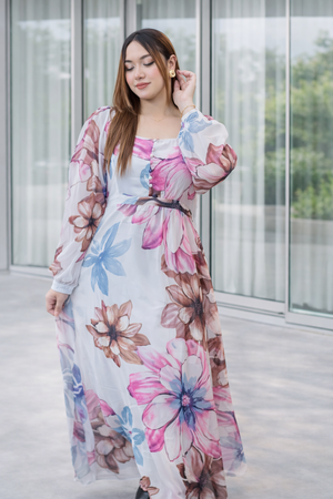 Woman wearing a floral dress standing in front of a glass building. Trendy Buzz.