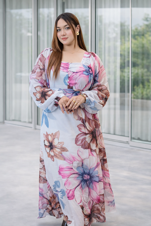 Woman wearing a floral dress standing in a modern indoor setting.