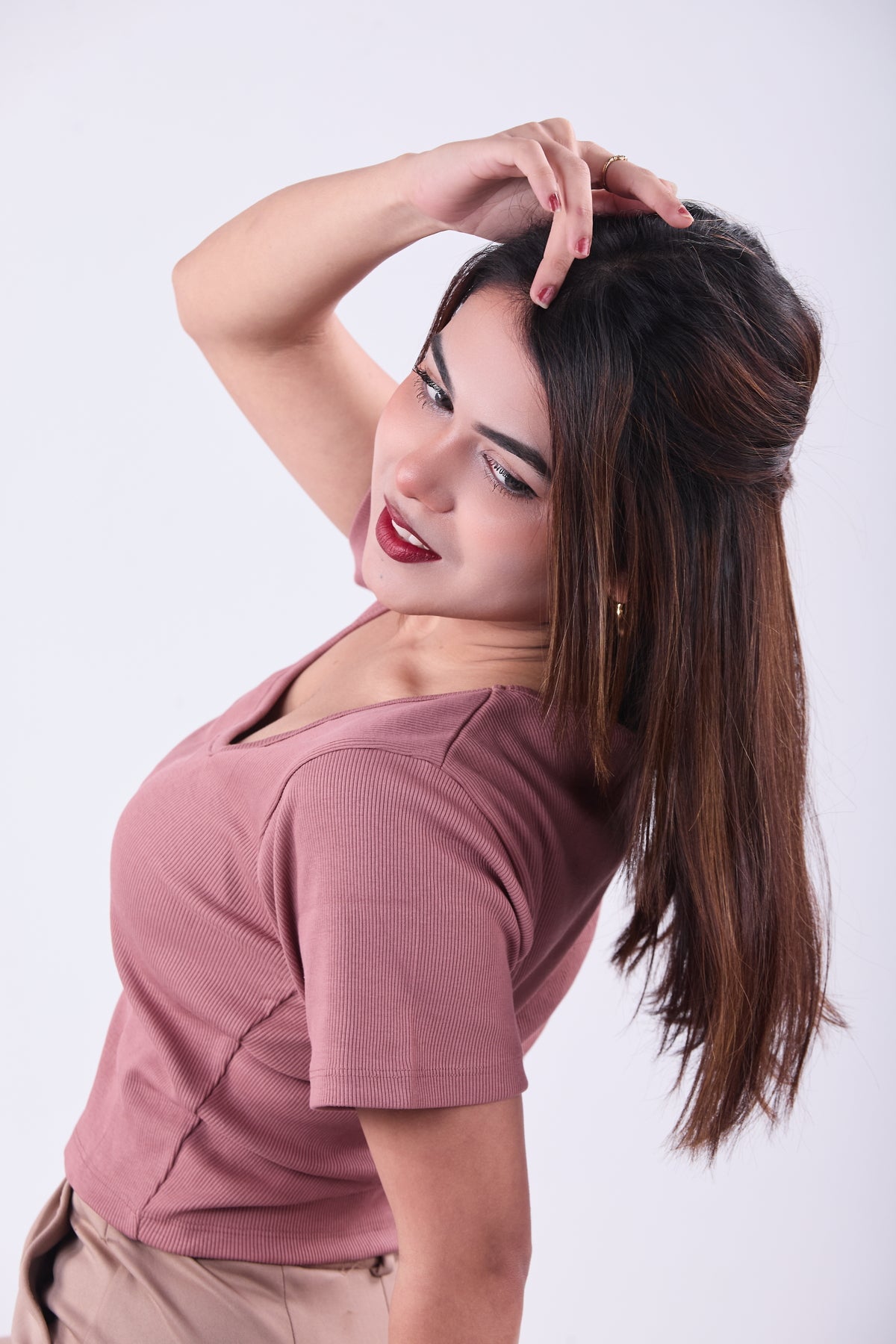 Woman with a high ponytail wearing a pink top on a white background