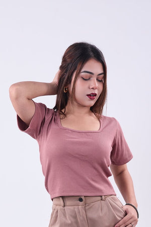 Woman wearing a pink top and beige pants on a white background