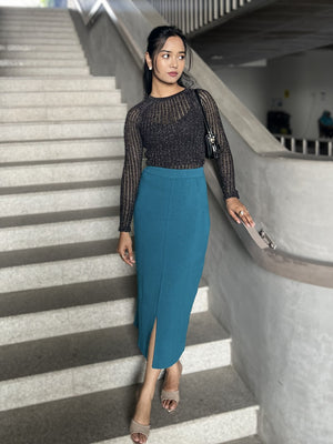 Woman in black top and teal skirt standing on a staircase