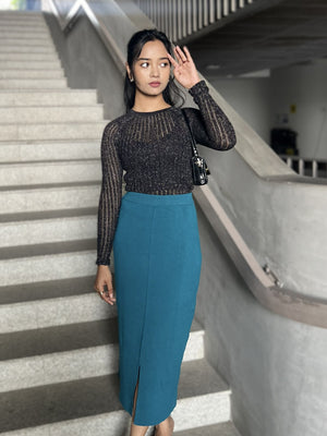 Woman in a black top and sea blue skirt standing on a staircase.