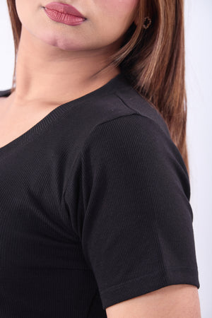 Close-up of a person wearing a black top with a plain background