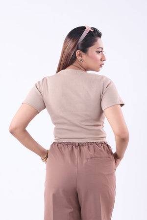 Woman wearing a beige top and brown pants on a white background