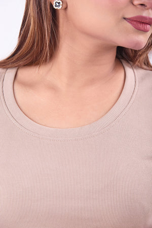 Close-up of a person wearing a beige ribbed sweater with a plain background