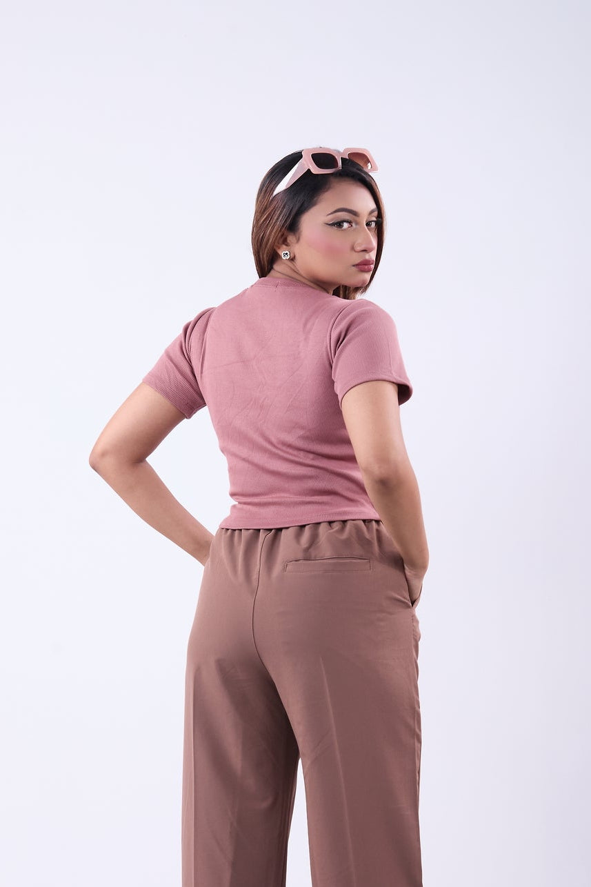 Woman wearing a pink top and brown pants on a white background