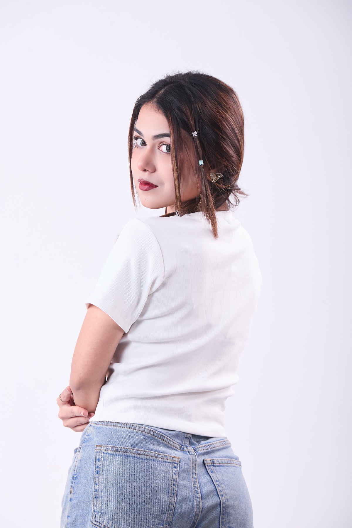 Woman wearing a white t-shirt and blue jeans on a white background