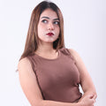 Woman wearing a brown sleeveless top and beige pants against a white background