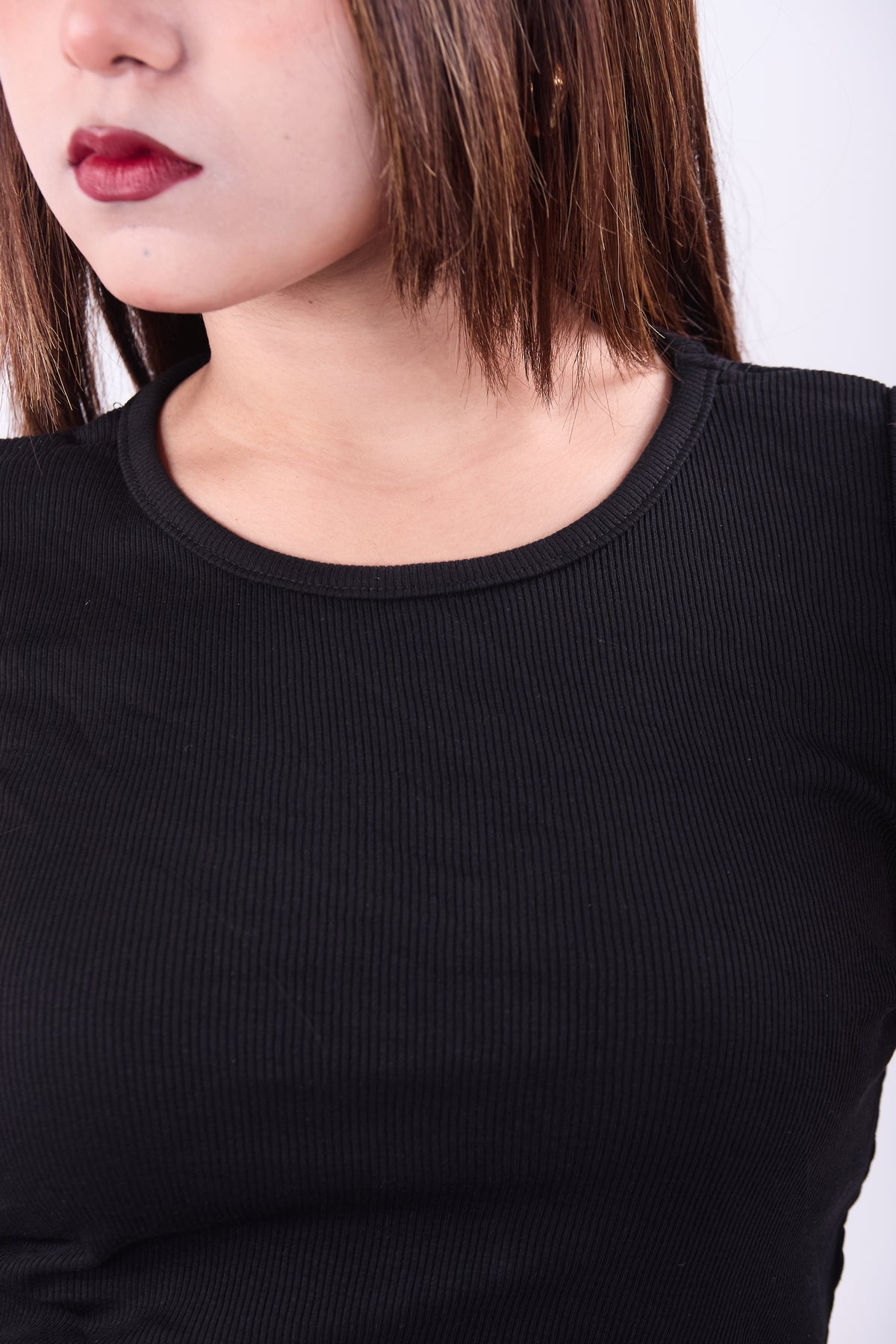 Close-up of a person wearing a black long-sleeve top against a white background