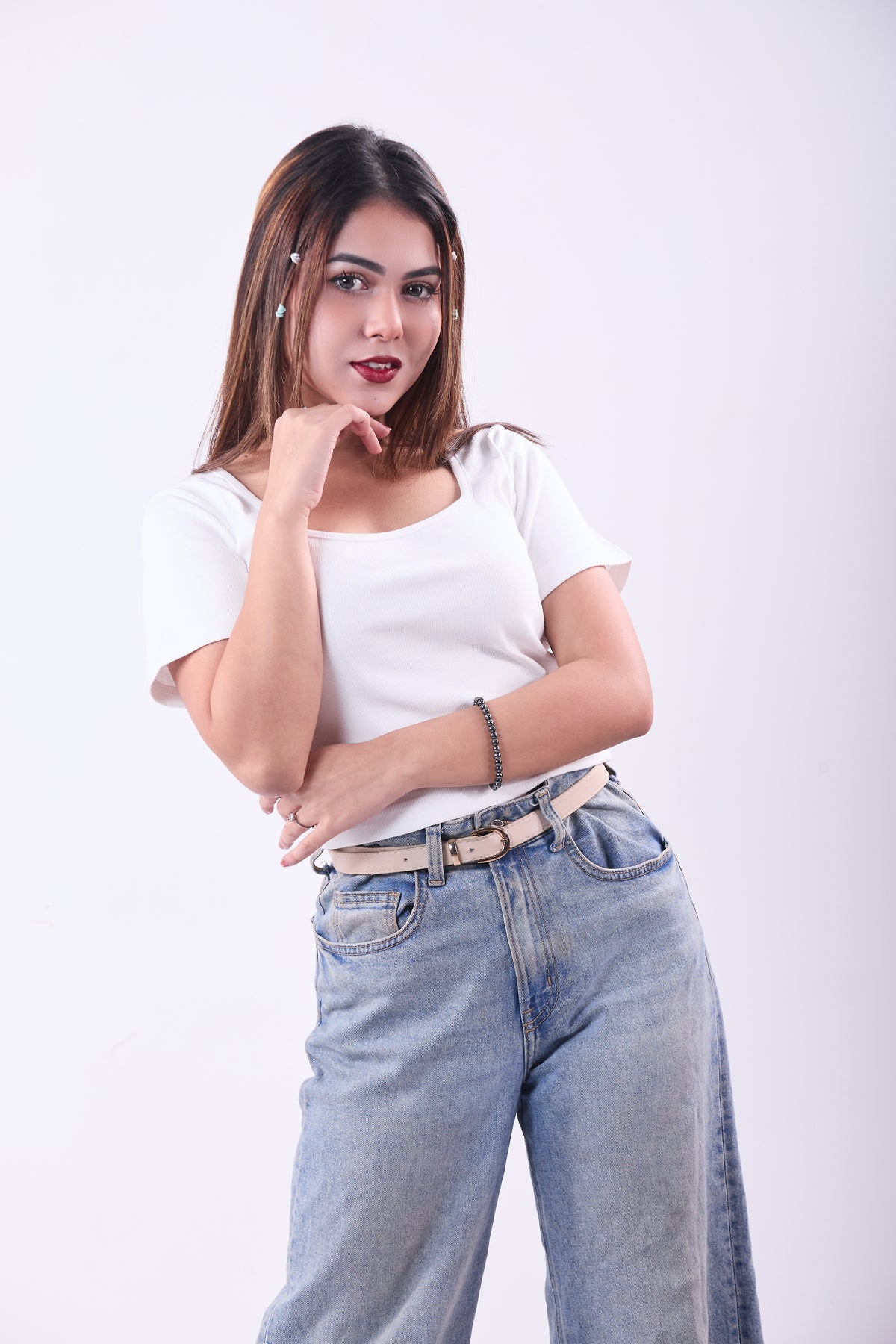 Woman wearing a white t-shirt and blue jeans on a white background