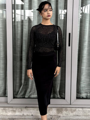 Woman wearing a black outfit standing in front of glass doors.