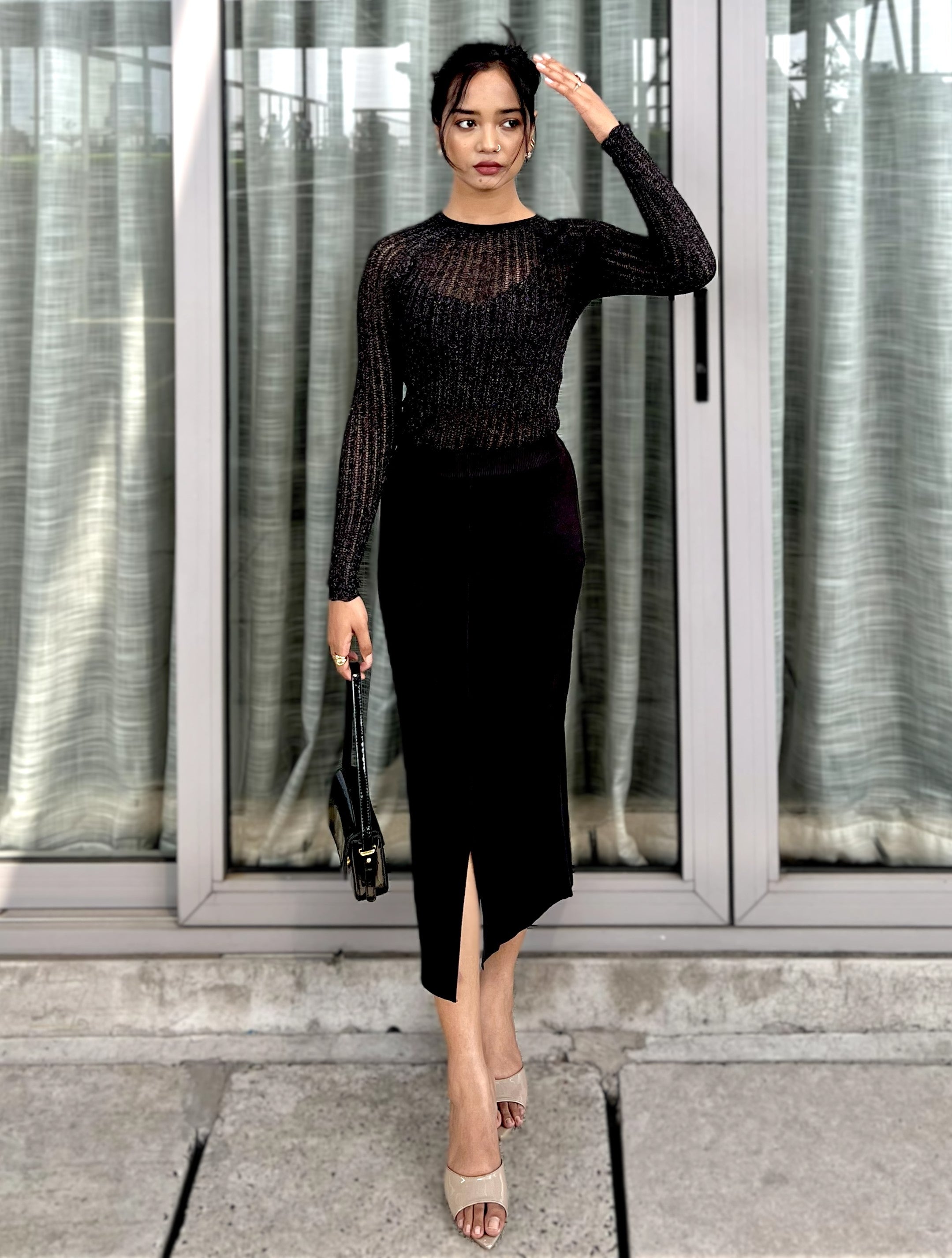 Woman in a black outfit standing in front of glass doors.