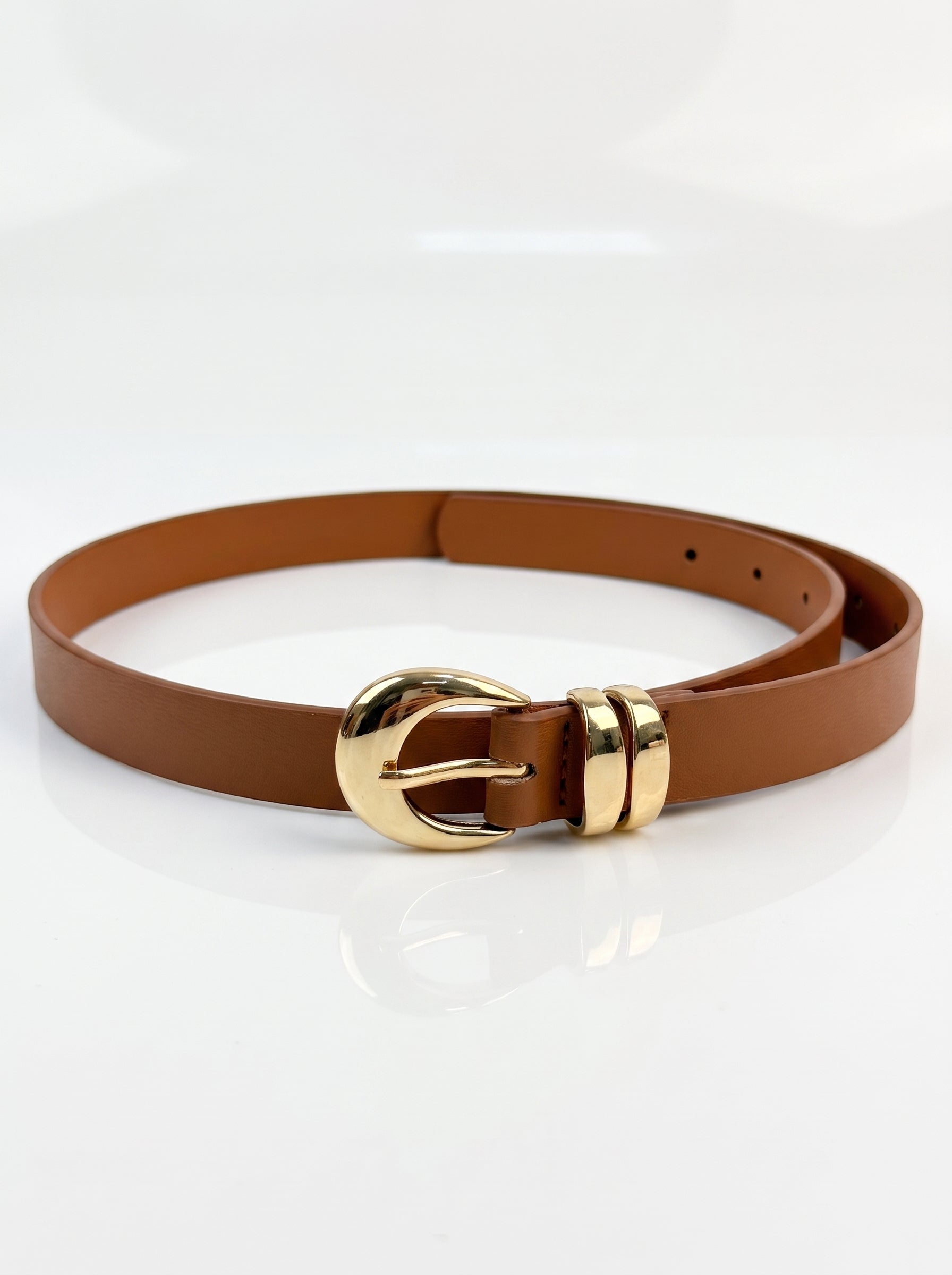 A brown leather belt with a polished gold-tone buckle, displayed on a clean white reflective surface.