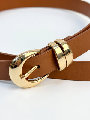 A close-up of a brown leather belt with a polished gold-tone buckle, resting on a clean white background.