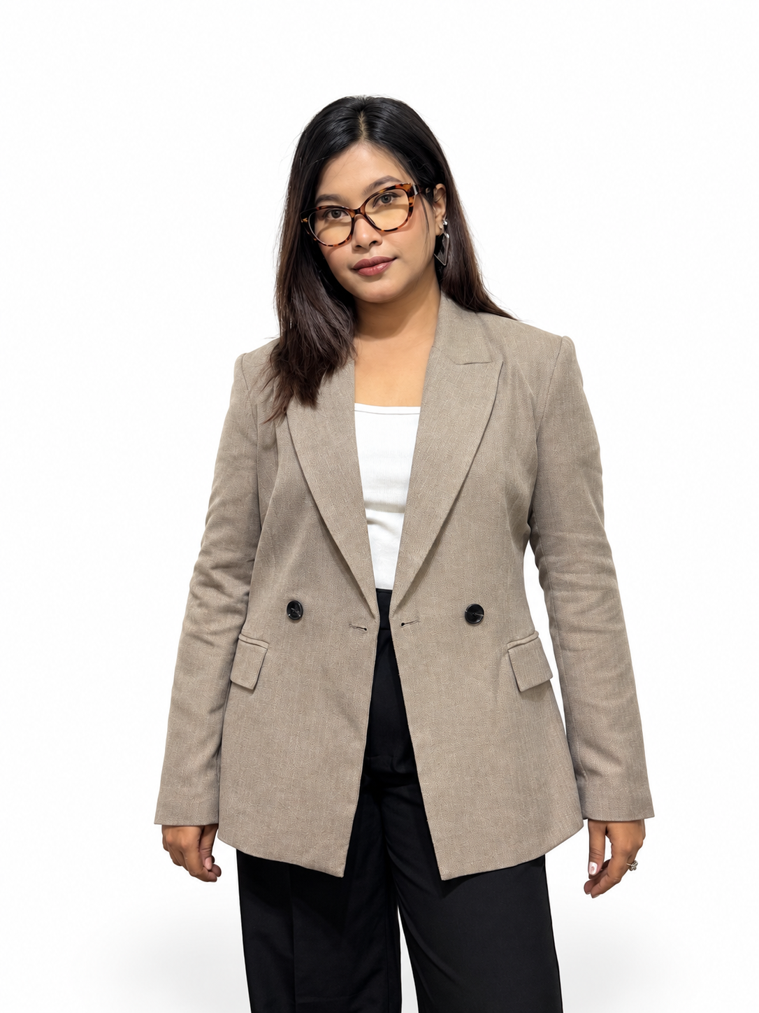 A woman modeling a light beige double-breasted blazer over a white top and black trousers, standing against a plain white studio background.