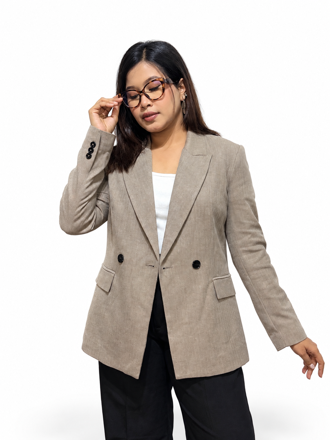 A woman modeling a light beige double-breasted blazer with black buttons, worn over a white top and black pants, against a plain white background.