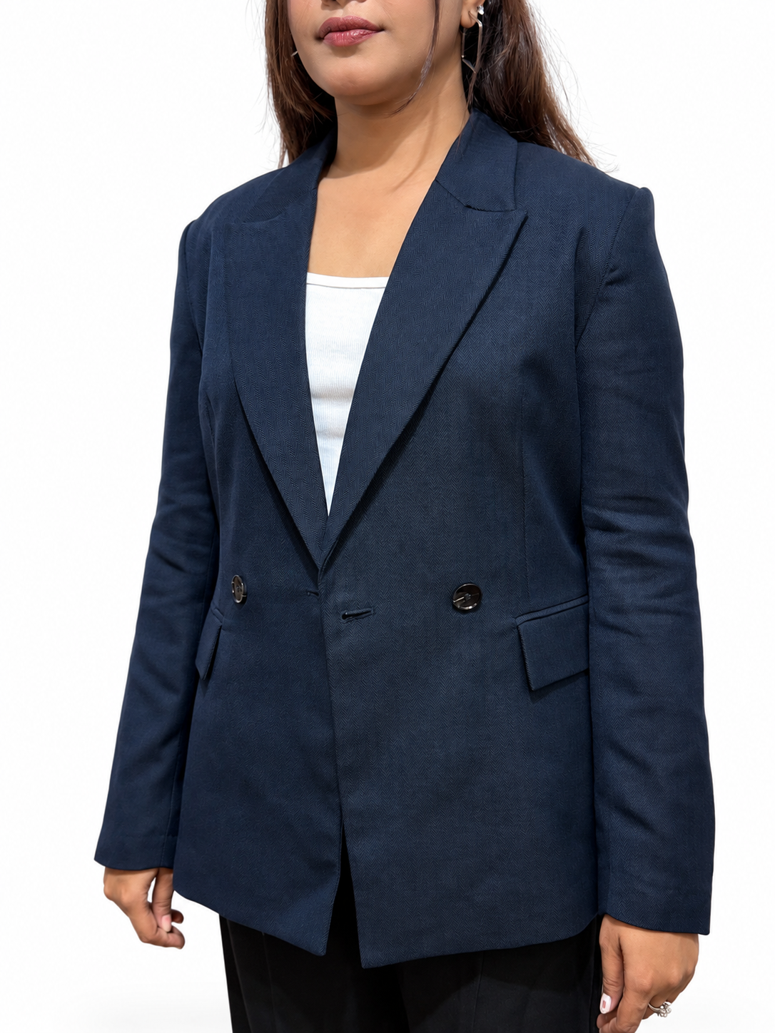 A woman wearing a navy blue double-breasted blazer over a white top and black pants, shown from the nose down against a plain white background.