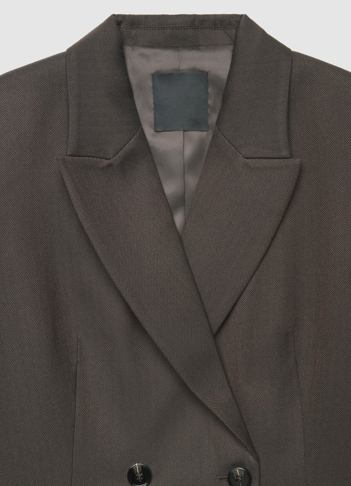 Close-up of a dark brown double-breasted blazer with notched lapels and a satin inner lining, shown against a light gray background.