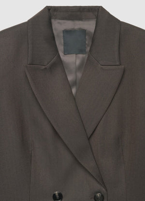 Close-up of a dark brown double-breasted blazer with notched lapels and a satin inner lining, shown against a light gray background.