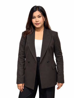 A woman modeling a dark brown double-breasted blazer over a white top and black pants, photographed against a plain white studio background.