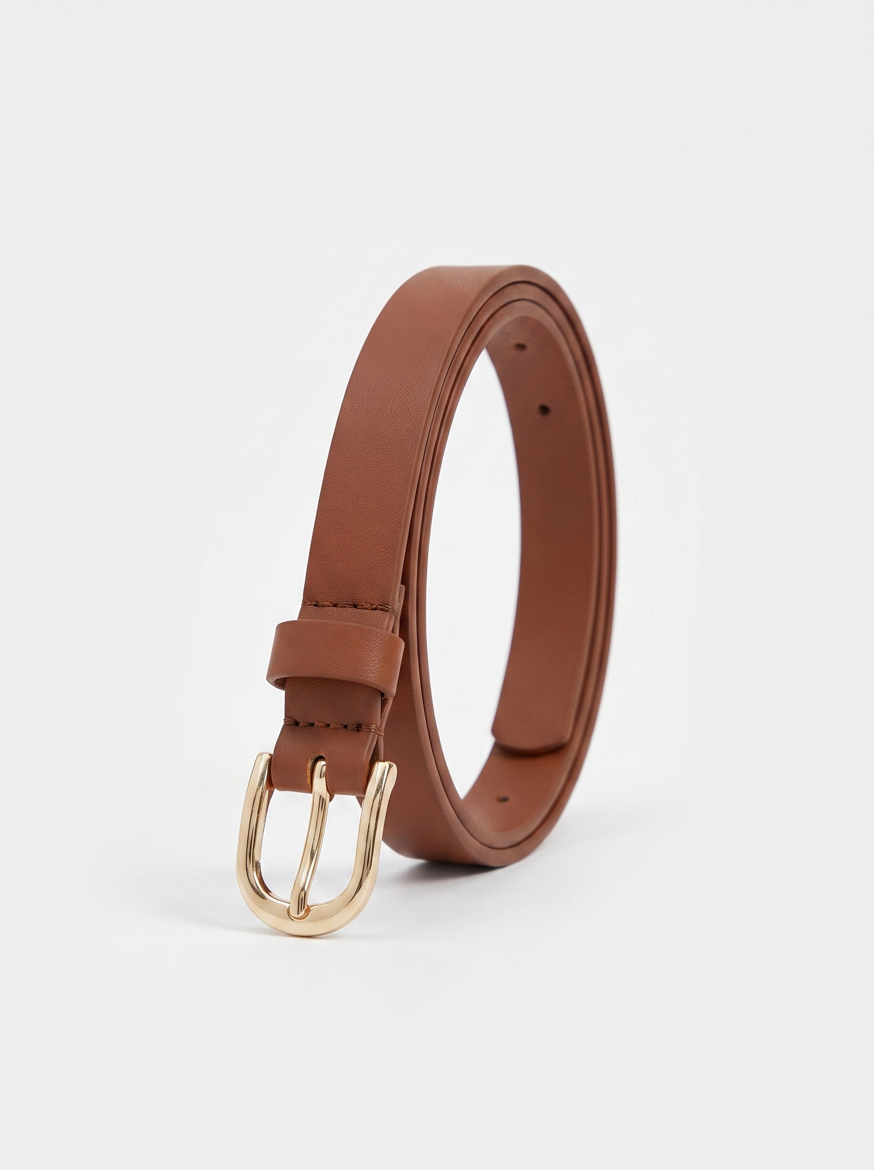 A brown leather belt with a gold-tone metal buckle, coiled and standing upright on a clean white background.
