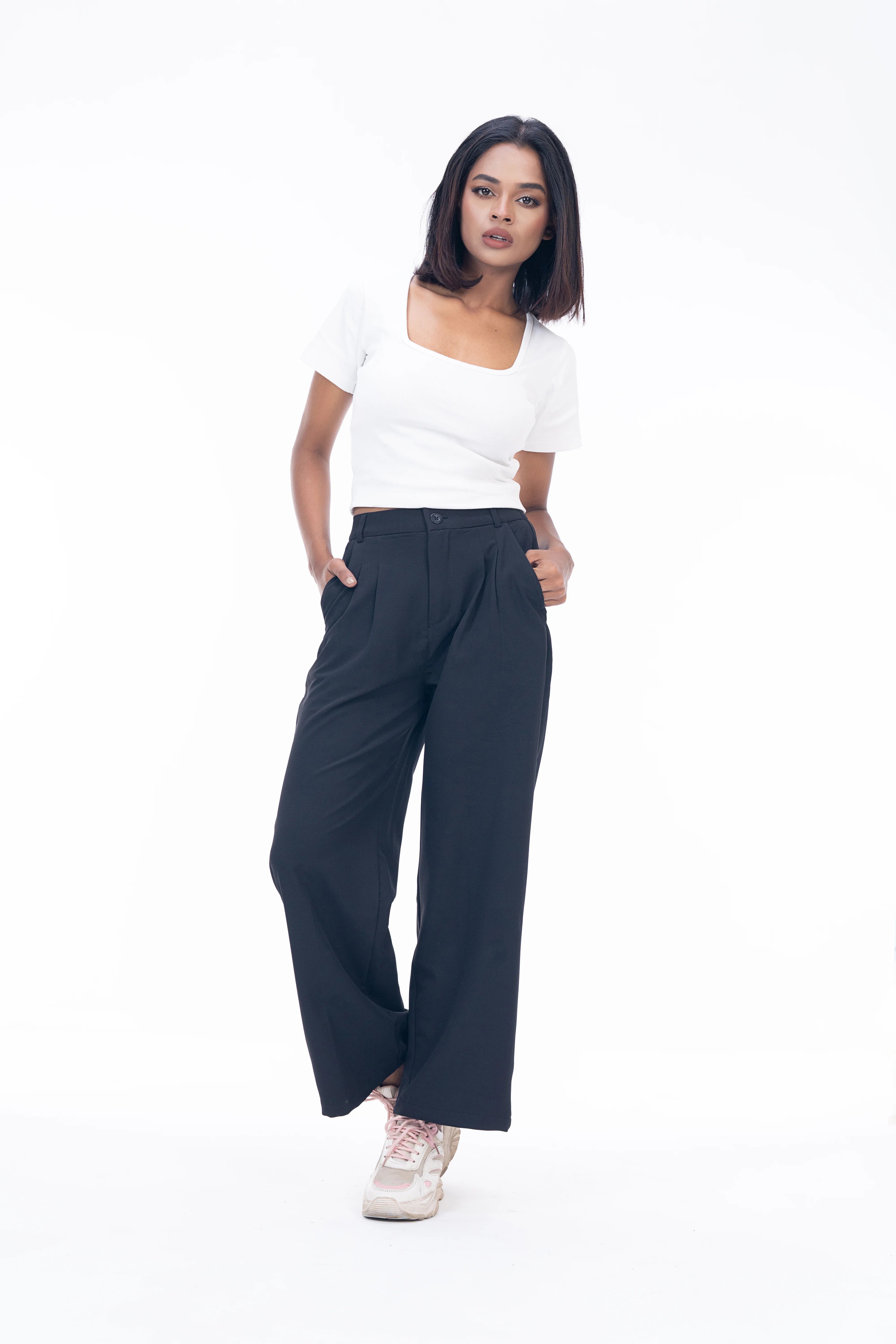 Woman wearing a white top and dark blue wide-leg pants on a white background