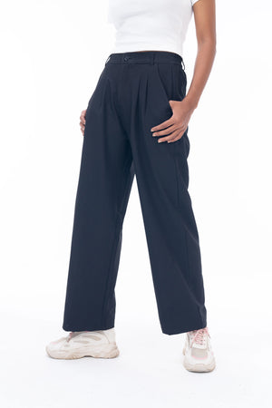 Person wearing navy pleated pants on a white background