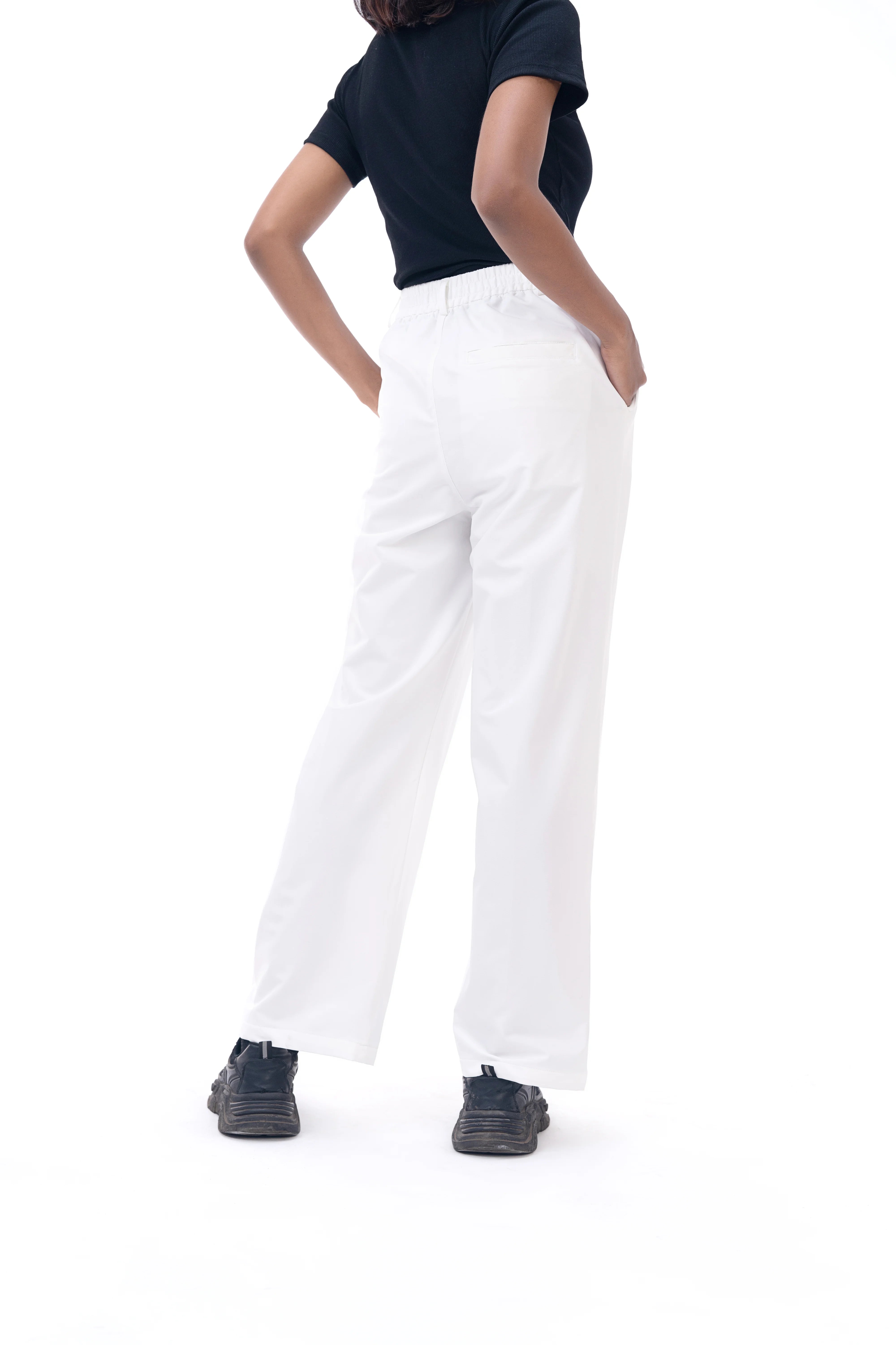 Person wearing a navy top and white pants on a white background
