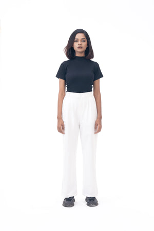 Person wearing a black top and white pants on a white background