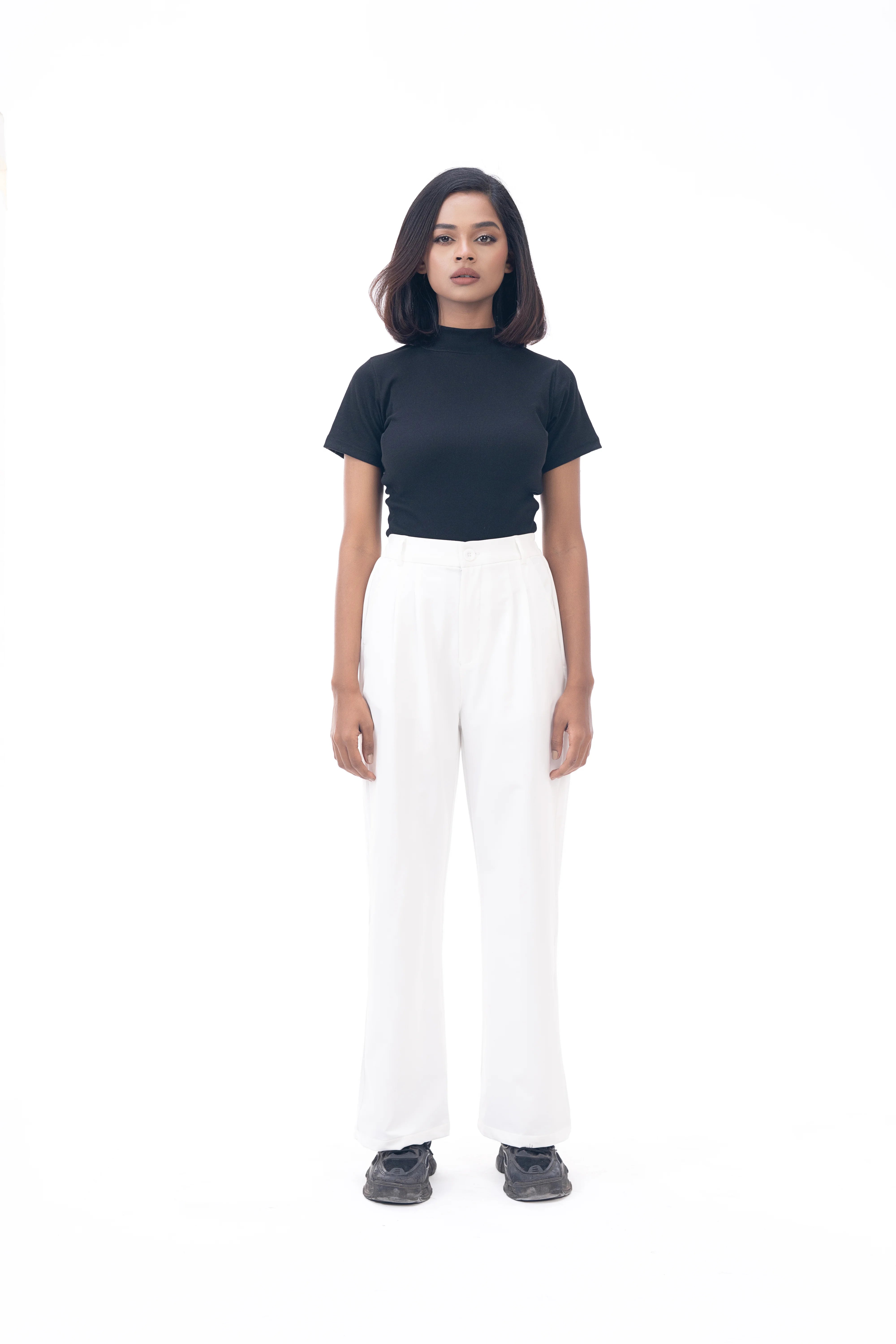 Person wearing a black top and white pants on a white background
